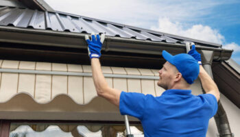 man installing house roof rain gutter system